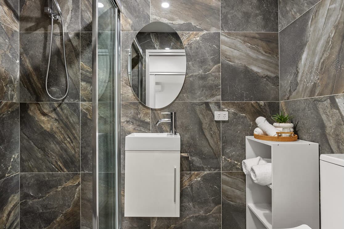 Dark marble ensuite with oval mirror at Fulica Street