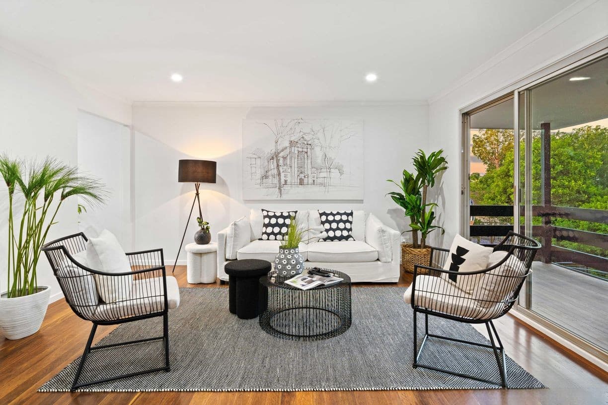Light-filled living room with timber floors, looking through to a covered deck